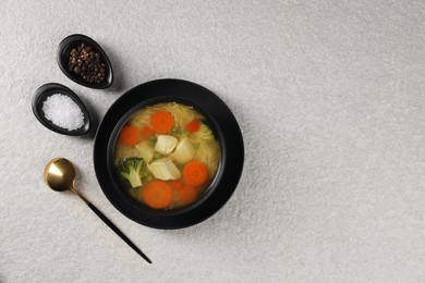 Tasty chicken soup with noodles and vegetables in bowl served on light textured table, flat lay. Space for text