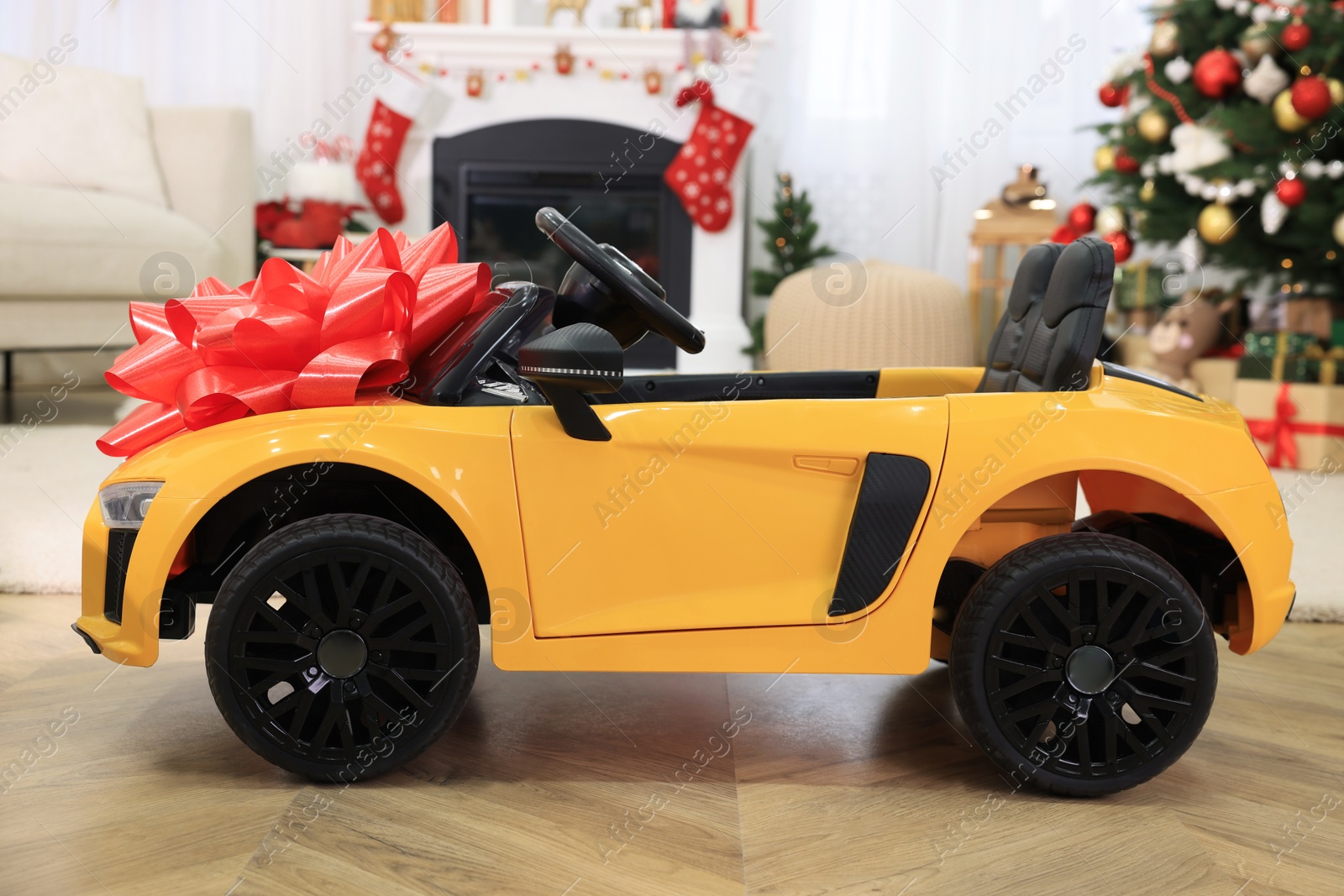 Photo of Children's electric toy car with red bow in room decorated for Christmas