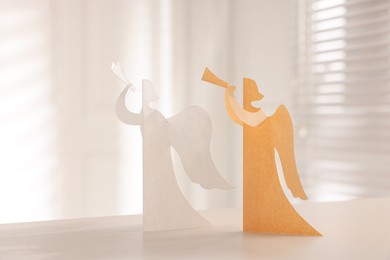 Photo of Beautiful angel paper cutouts on white table indoors