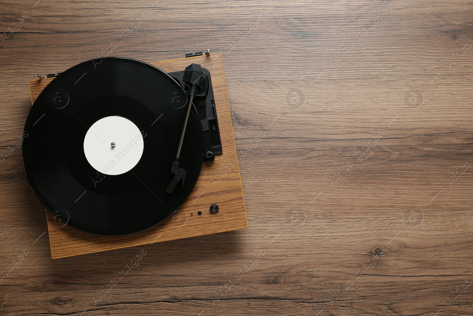 Photo of Turntable with vinyl record on wooden background, top view. Space for text