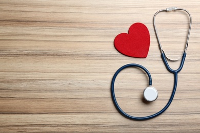 Photo of Stethoscope and red heart on wooden background, flat lay with space for text. Health insurance concept