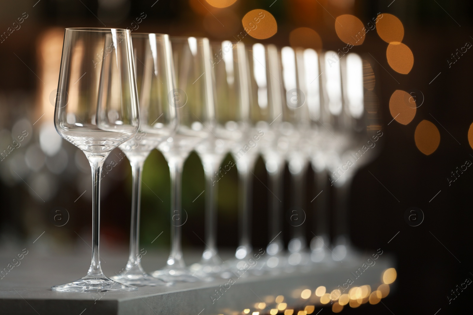 Photo of Set of empty wine glasses on grey table against blurred background