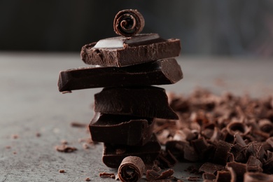 Photo of Curls and pieces of tasty chocolate on gray table
