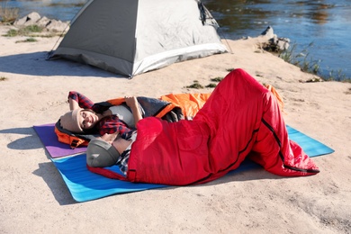 Photo of Campers lying in sleeping bags on wild beach