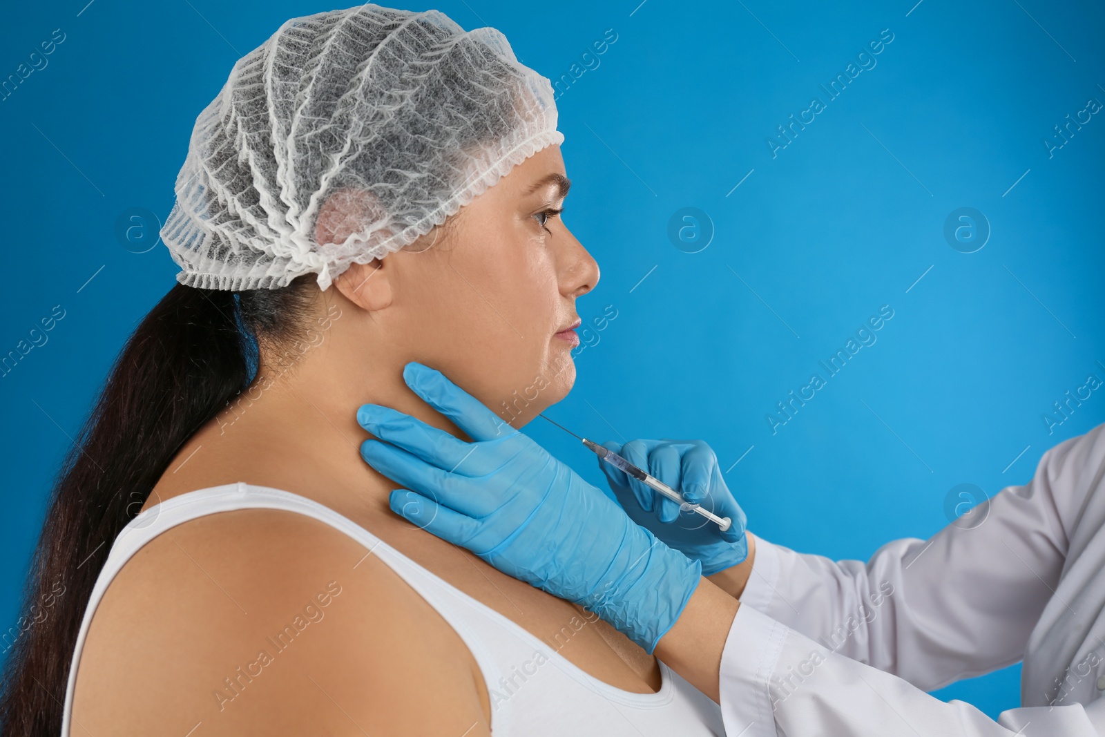 Photo of Woman with double chin getting injection on blue background. Cosmetic surgery