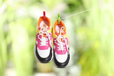 Stylish sneakers drying on washing line against blurred background