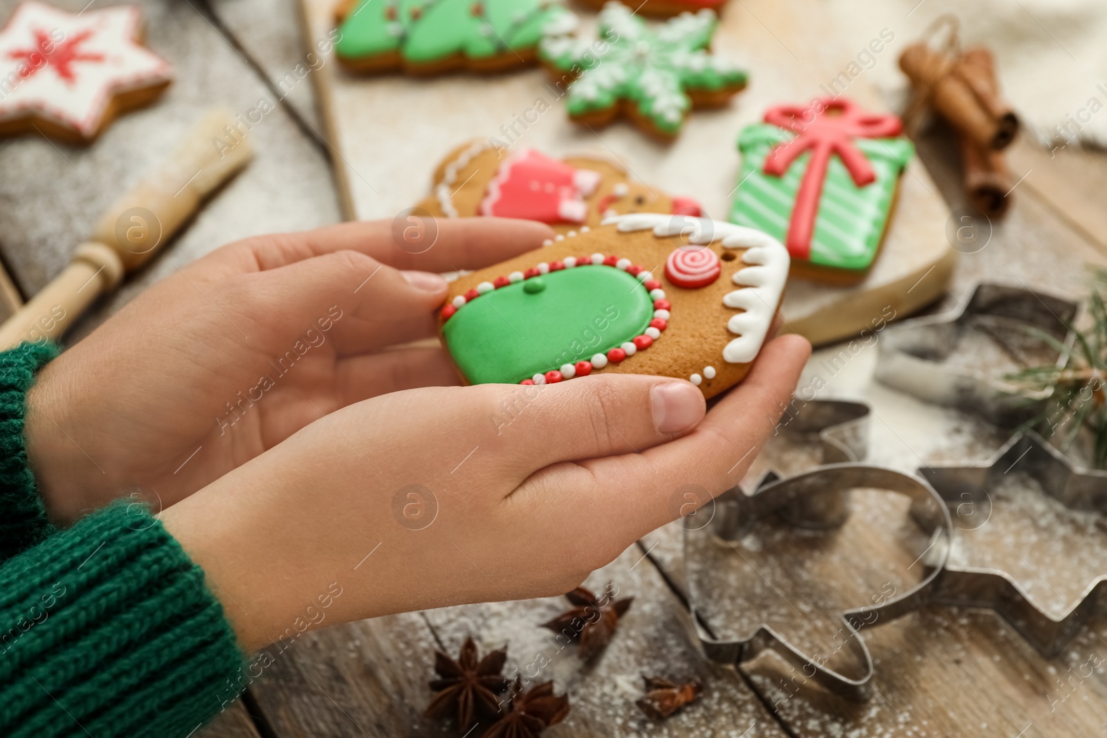 Photo of Woman holding delicious homemade Christmas cookie at wooden table, closeup