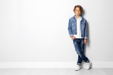 Photo of Cute little boy in casual outfit near white wall. Space for text