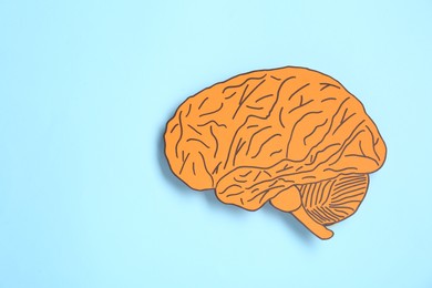 Photo of Paper cutout of human brain on light blue background, top view. Space for text