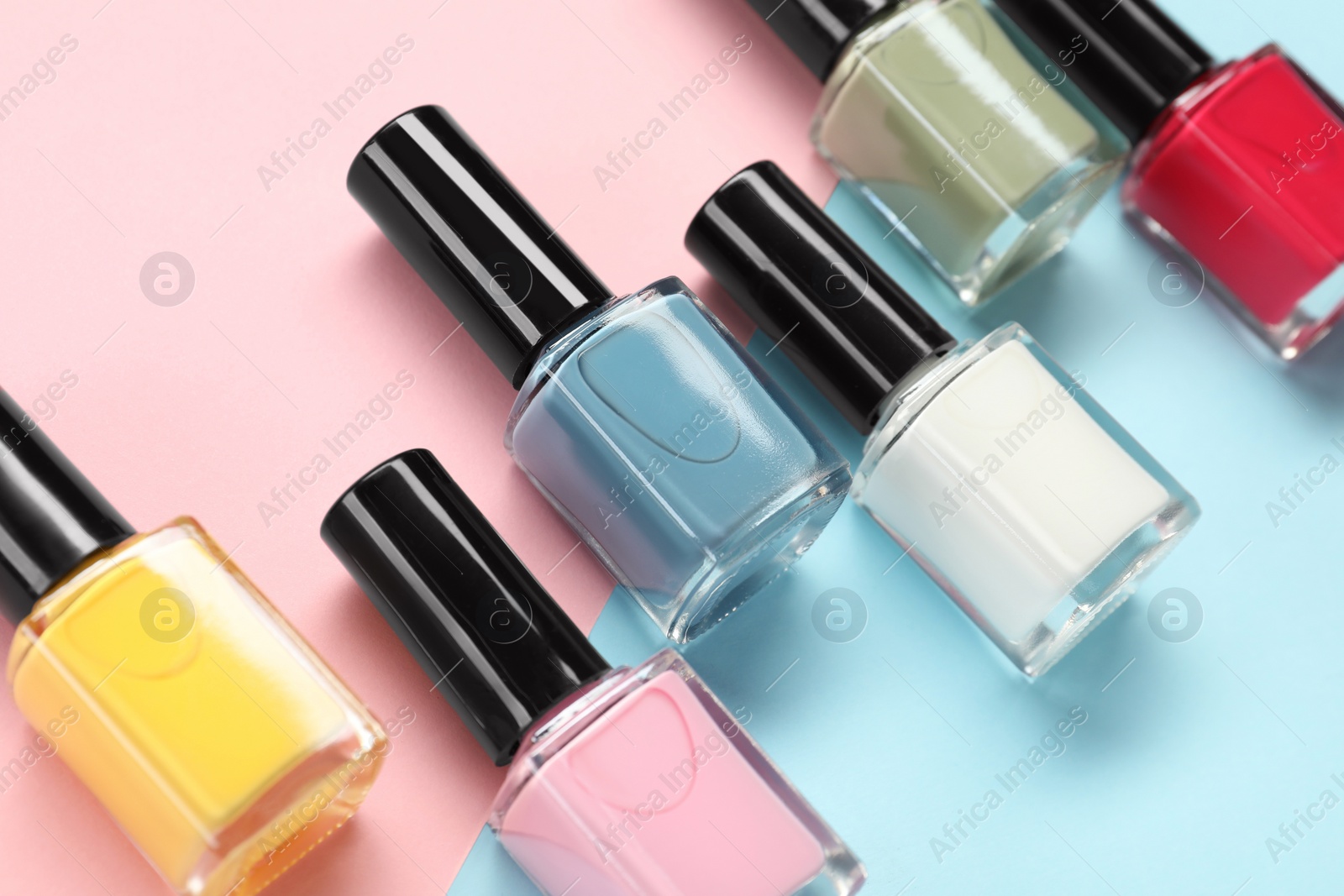 Photo of Bright nail polishes in bottles on color background, closeup
