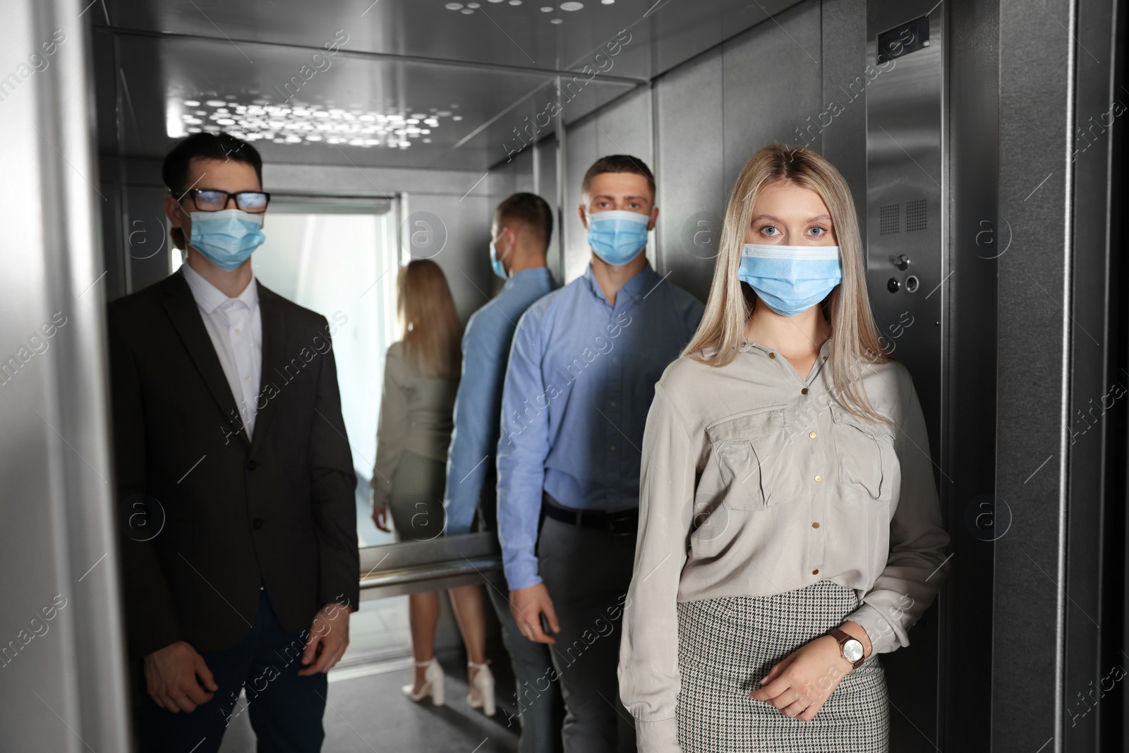 Photo of Group of people with face masks in elevator. Protective measure