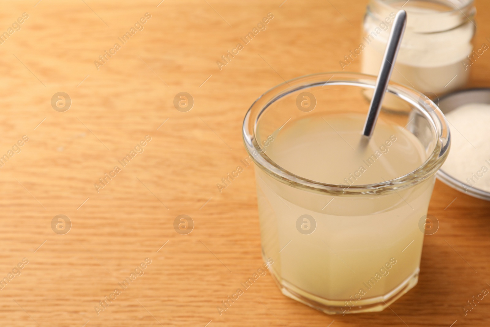 Photo of Agar-agar jelly and powder on wooden table, closeup. Space for text