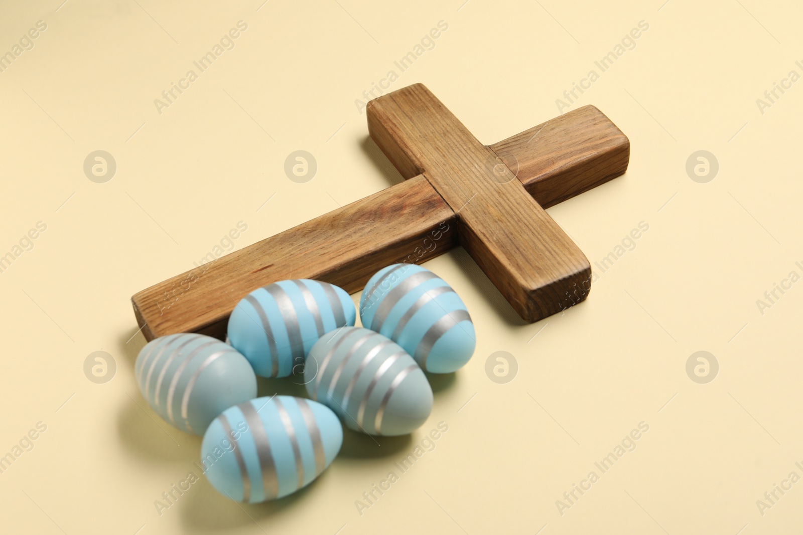 Photo of Wooden cross and painted Easter eggs on beige background