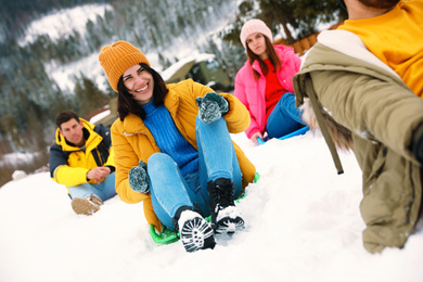 Photo of Group of friends having fun and sledding on snow. Winter vacation