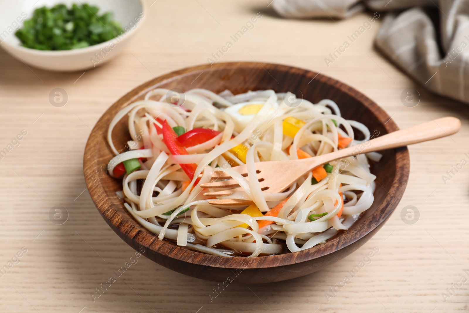 Photo of Bowl of noodles with vegetables on wooden background