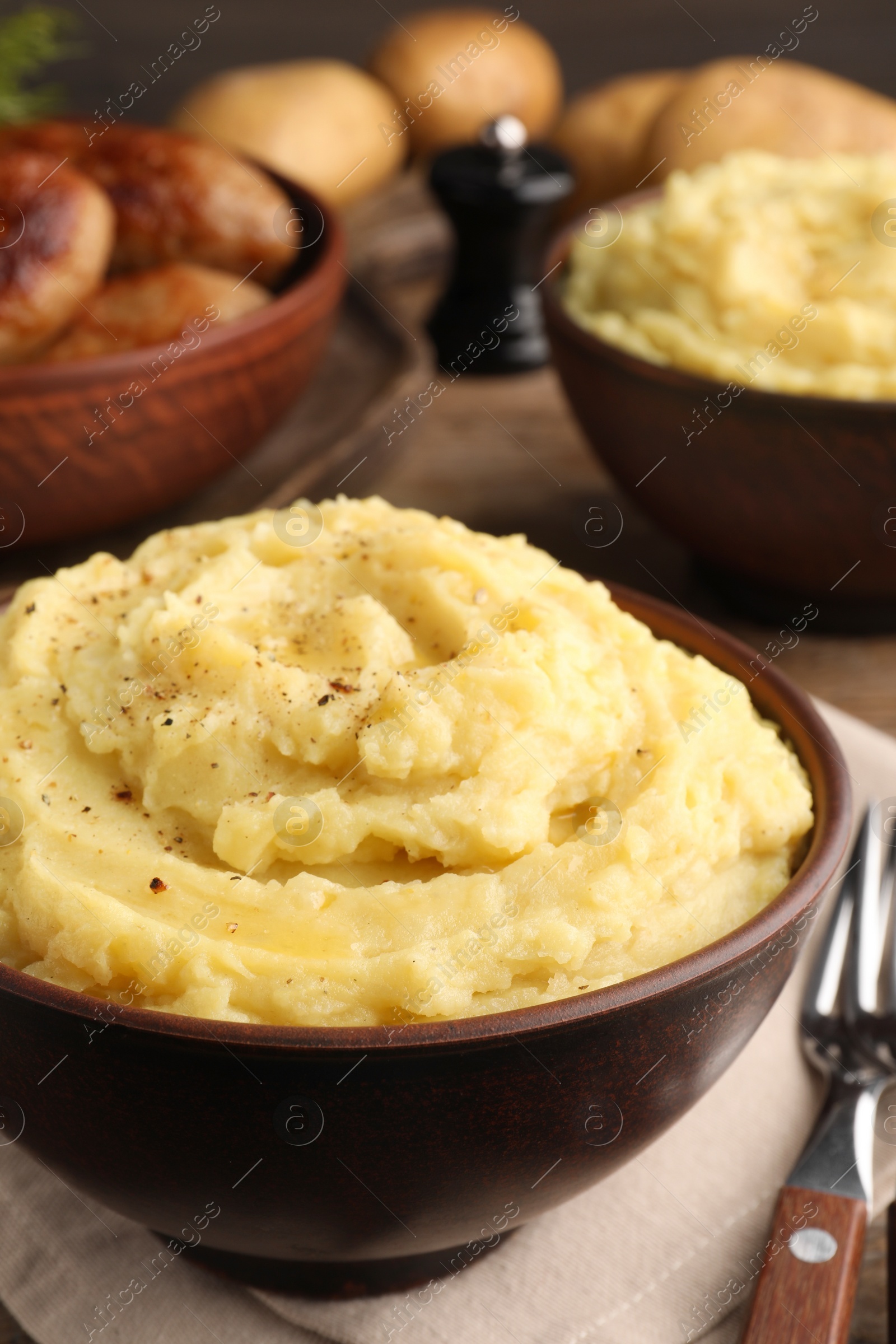 Photo of Bowl of tasty mashed potatoes with black pepper on table, closeup