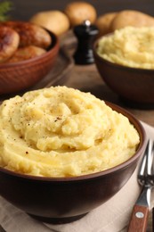 Bowl of tasty mashed potatoes with black pepper on table, closeup