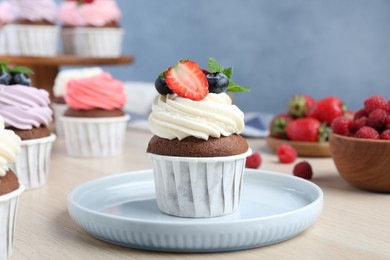 Photo of Sweet cupcake with fresh berries on light wooden table