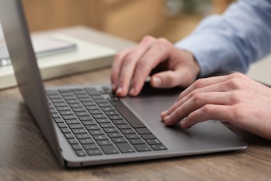 Photo of E-learning. Man using laptop during online lesson at table indoors, closeup