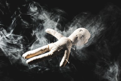 Image of Voodoo doll with pins and smoke on dark background