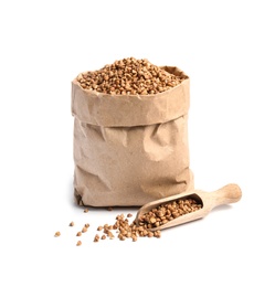 Paper bag and scoop with uncooked buckwheat on white background