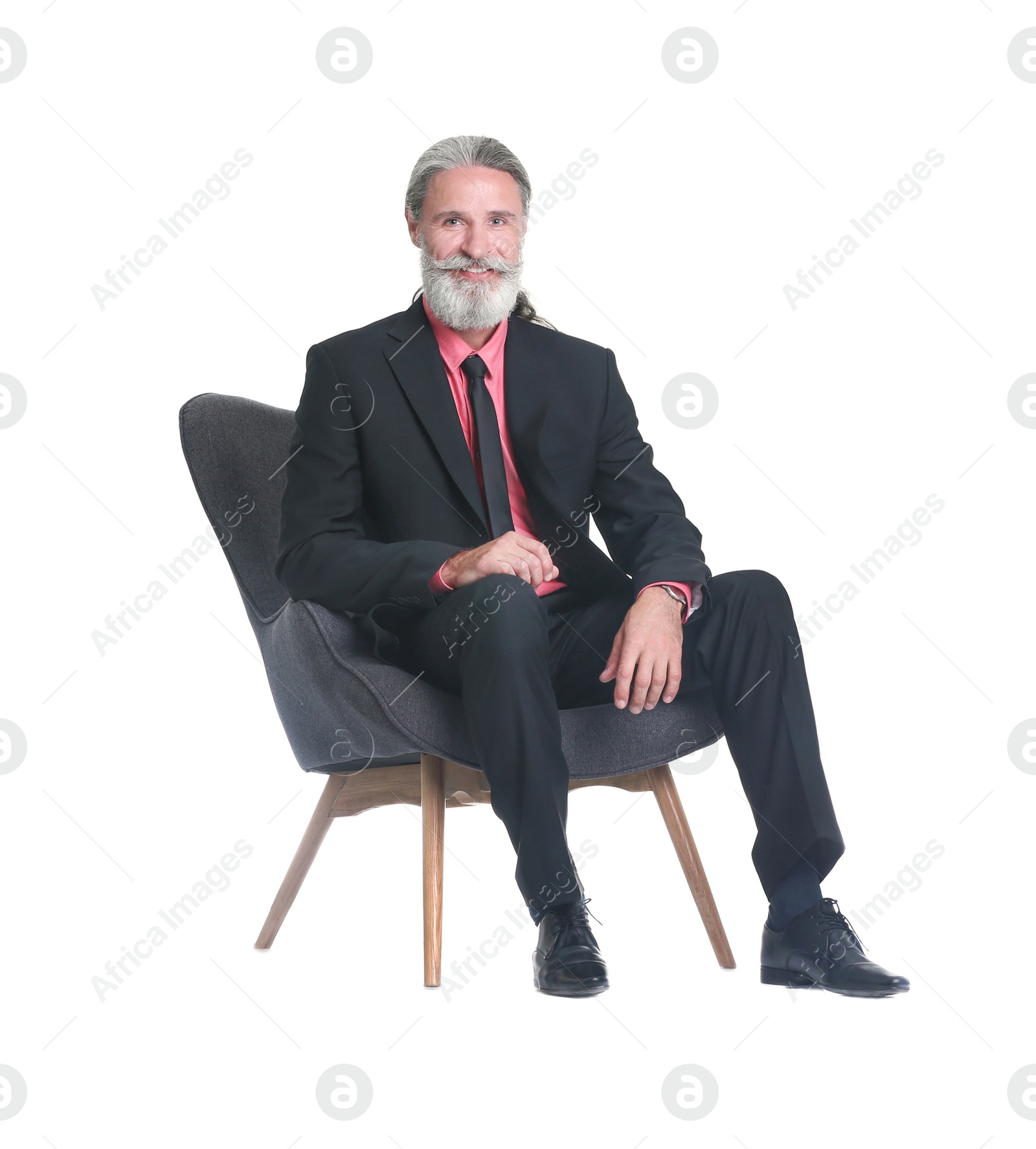 Photo of Handsome bearded mature man in suit sitting in armchair on white background