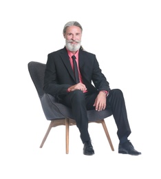 Photo of Handsome bearded mature man in suit sitting in armchair on white background