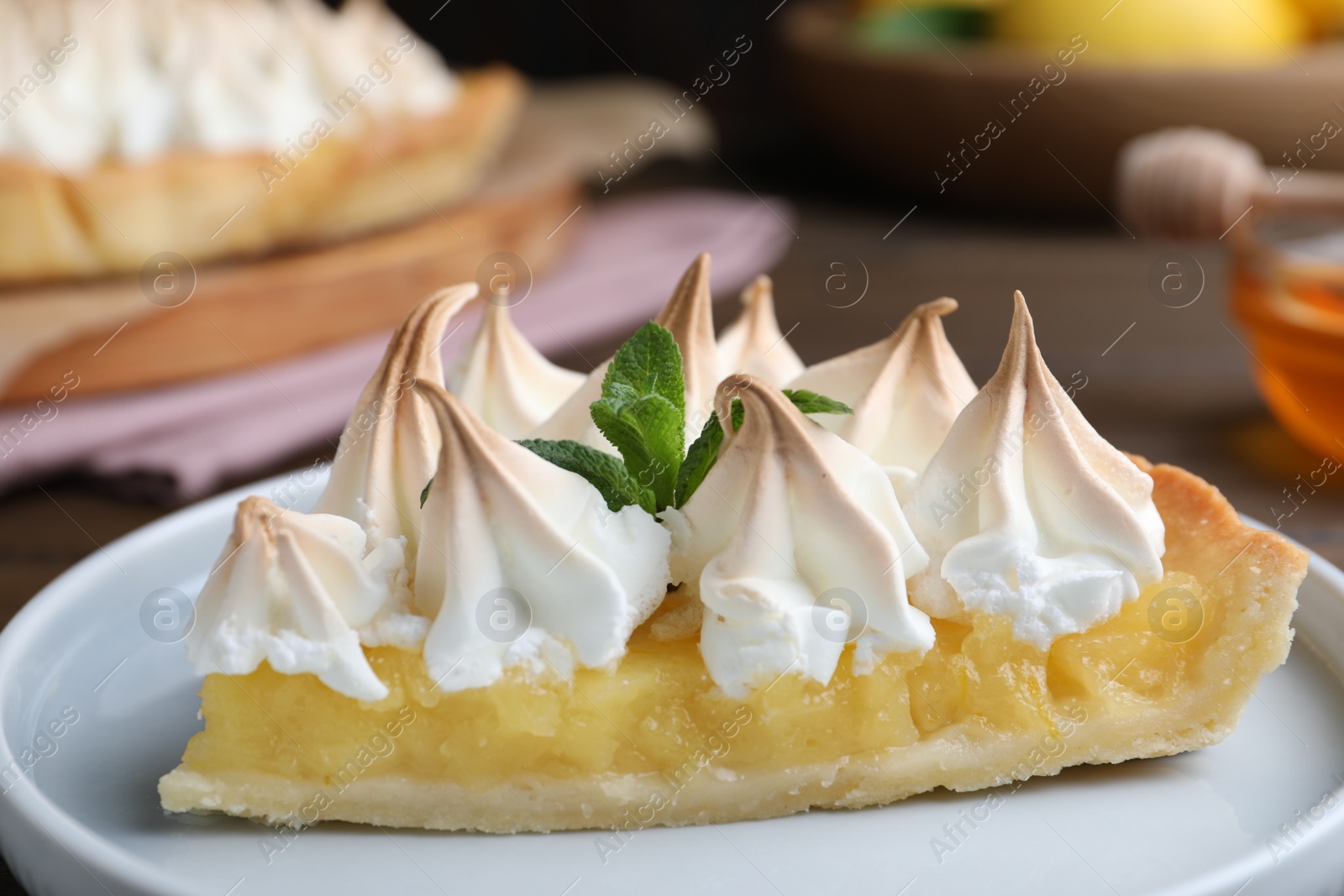 Photo of Piece of delicious lemon meringue pie with mint on plate, closeup