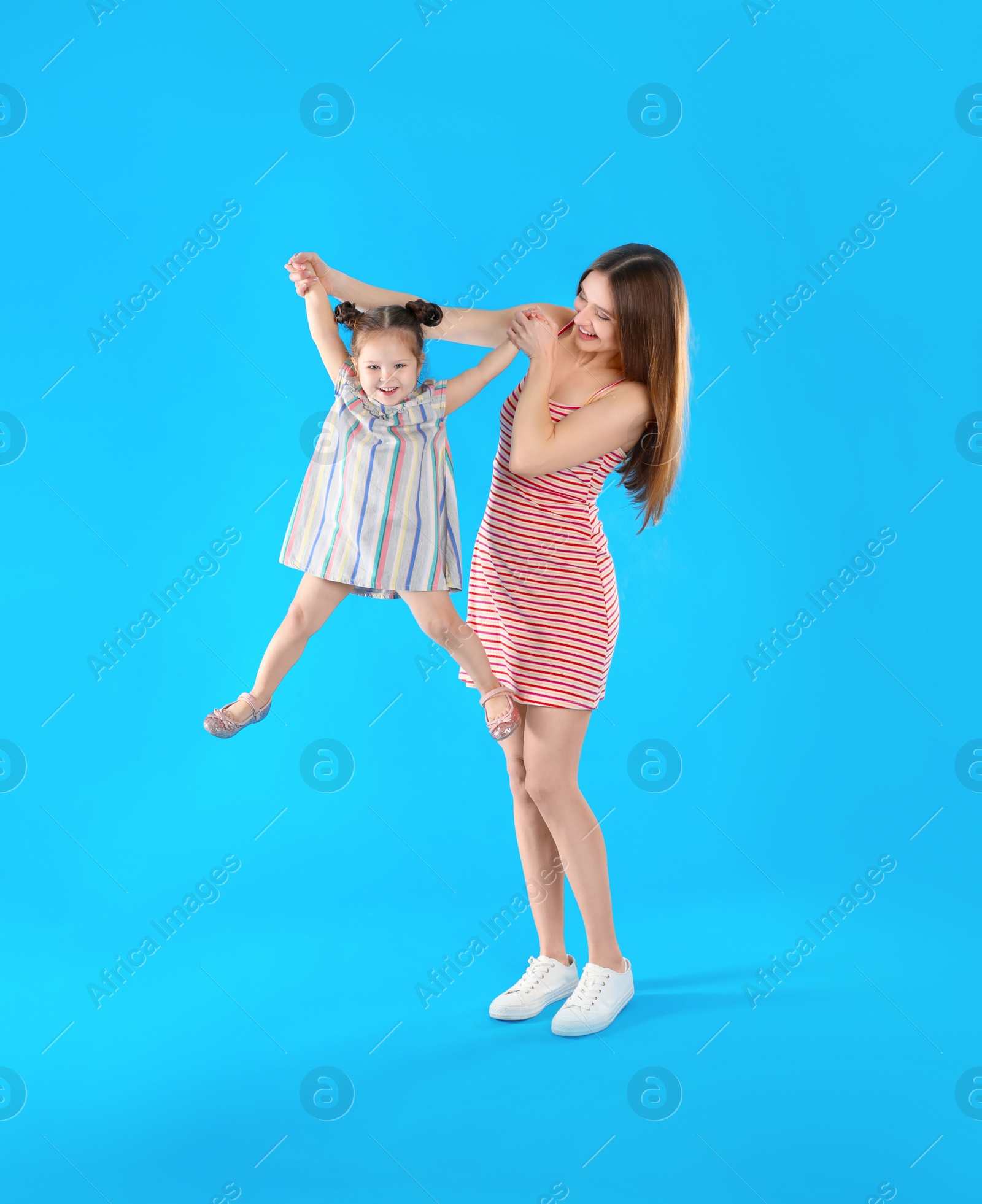 Photo of Young mother and little daughter having fun on light blue background