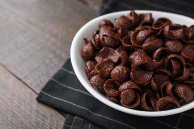 Photo of Breakfast cereal. Chocolate corn flakes in bowl on wooden table, closeup. Space for text