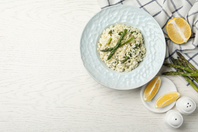 Photo of Delicious risotto with asparagus on white wooden table, flat lay. Space for text
