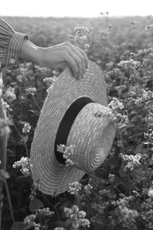 Image of Woman with hat in beautiful blossoming field, closeup. Black and white effect