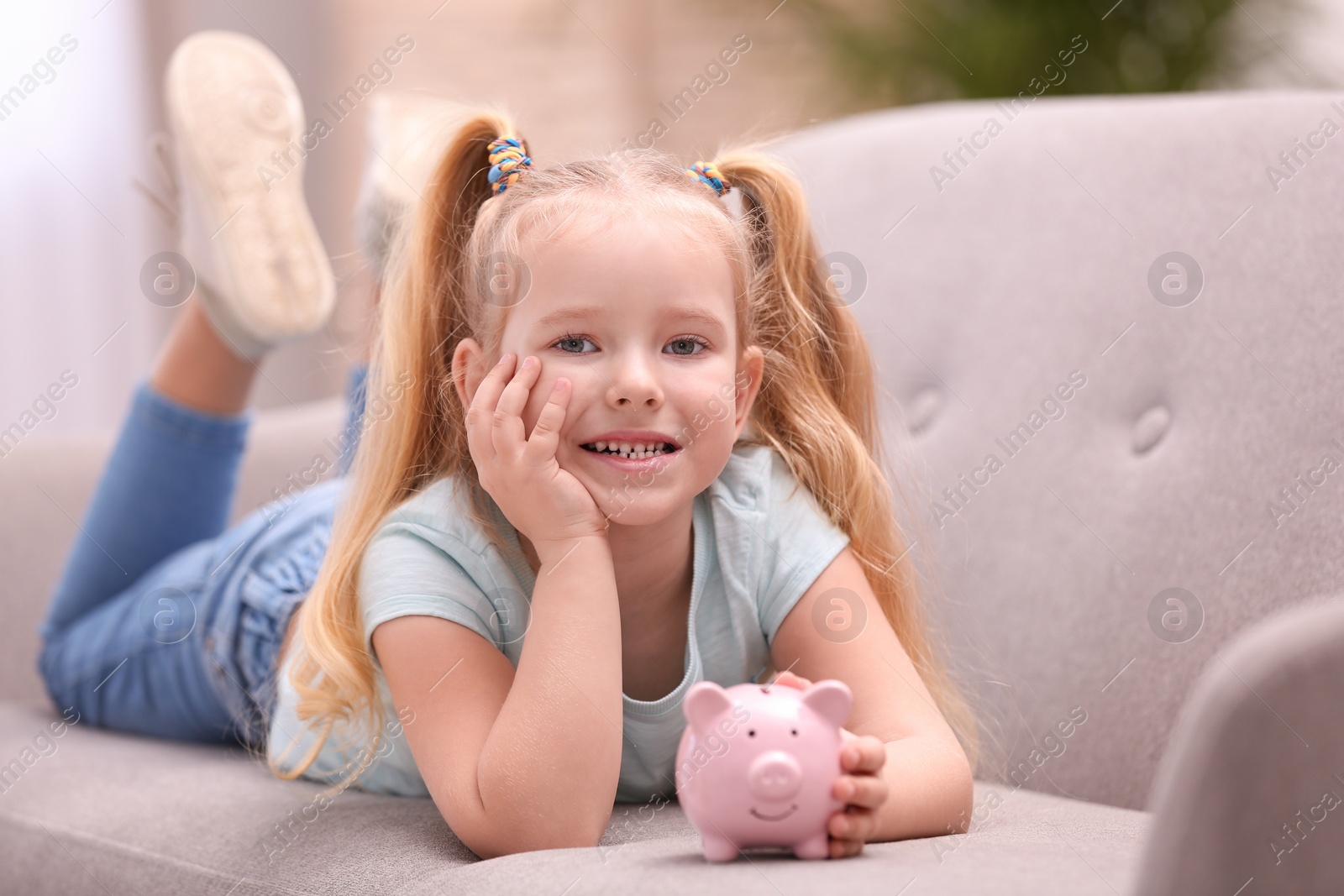 Photo of Little girl with piggy bank at home
