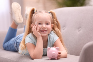 Little girl with piggy bank at home