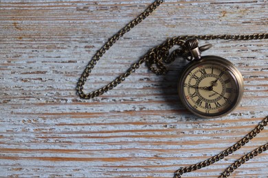 Pocket clock with chain on old wooden table, top view. Space for text