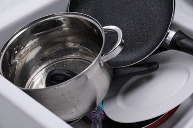 Photo of Many different clean dishes in sink, closeup