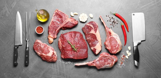 Photo of Fresh raw beef cuts, spices and butcher tools on light grey textured table, flat lay