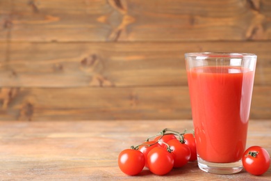 Photo of Delicious tomato juice and vegetables on wooden table. Space for text