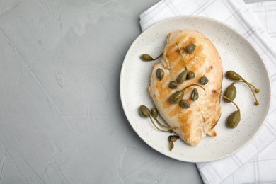 Delicious cooked chicken fillet with capers served on light grey table, top view. Space for text