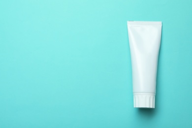 Photo of Blank tube of toothpaste on color background, top view with space for text