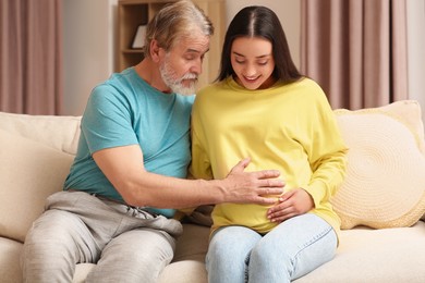 Photo of Happy pregnant woman spending time with her father at home. Grandparents' reaction to future grandson