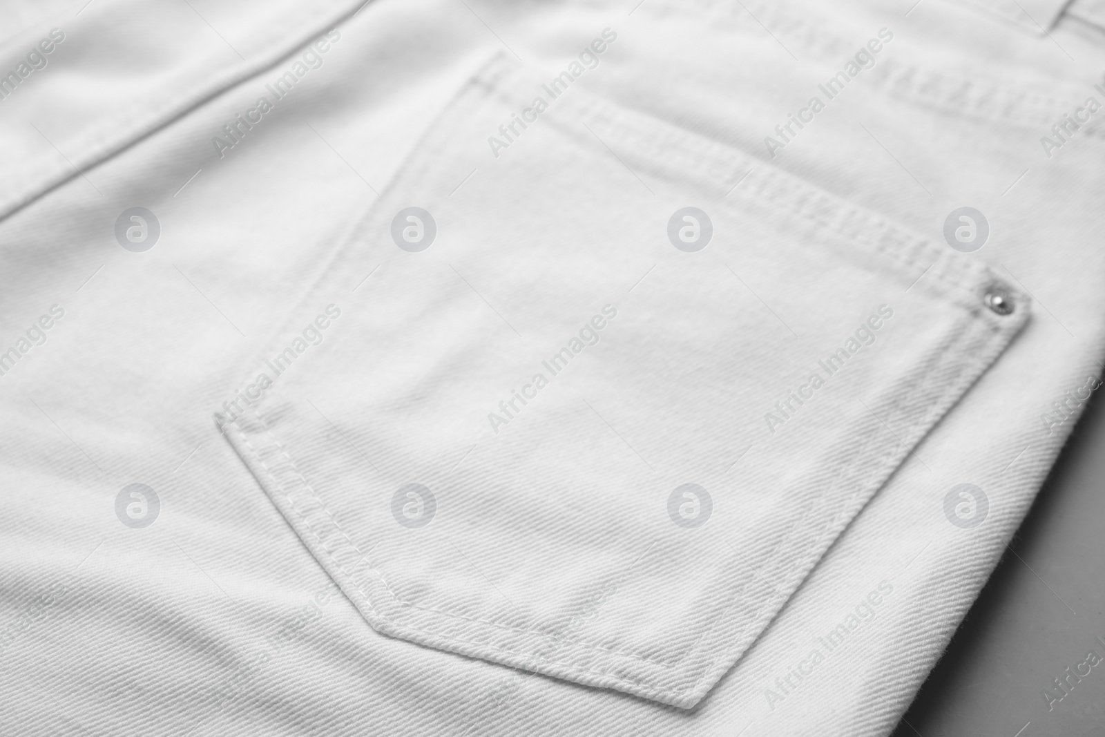 Photo of White jeans with pocket on grey background, closeup