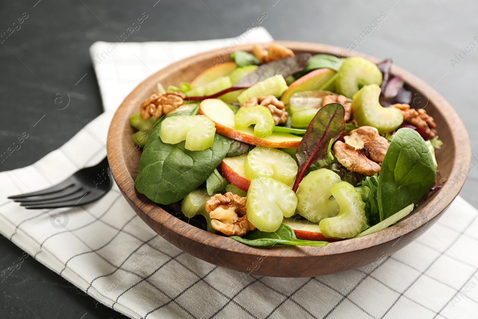 Photo of Delicious fresh celery salad on black table, closeup