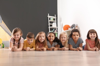 Cute little children lying on floor in kindergarten. Indoor activity