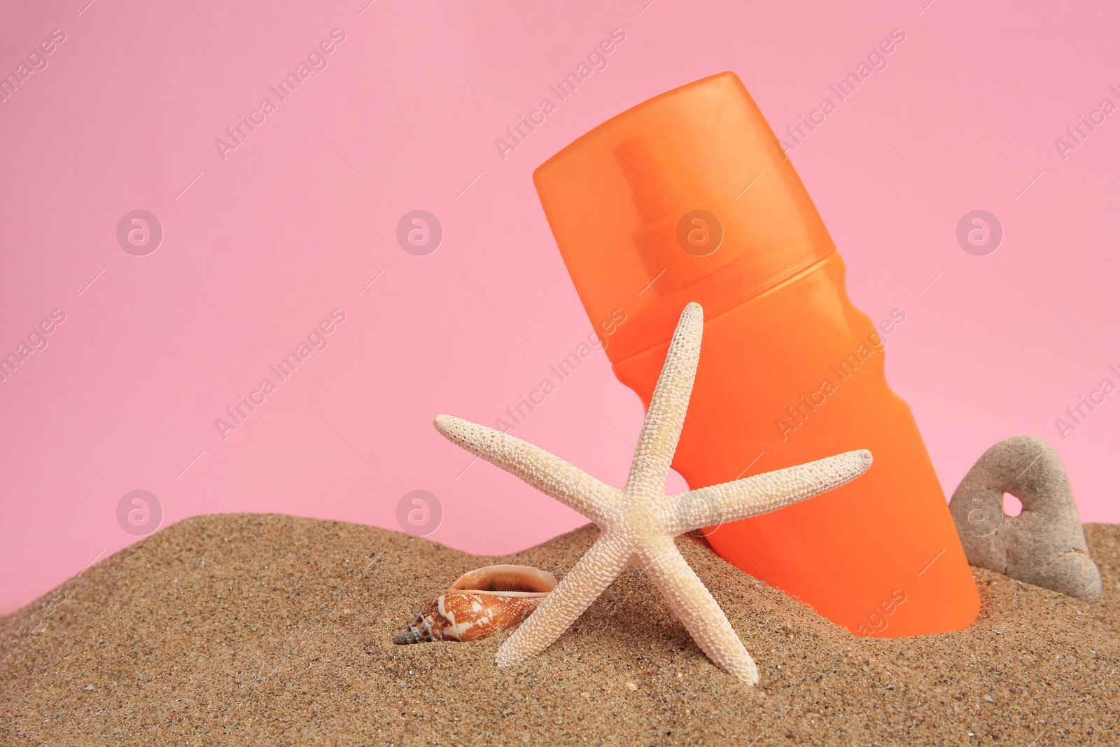 Photo of Sand with sunscreen, starfish, stone and seashell against pink background, space for text. Sun protection care