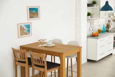 Stylish kitchen interior with dining table and bar stools near white wall