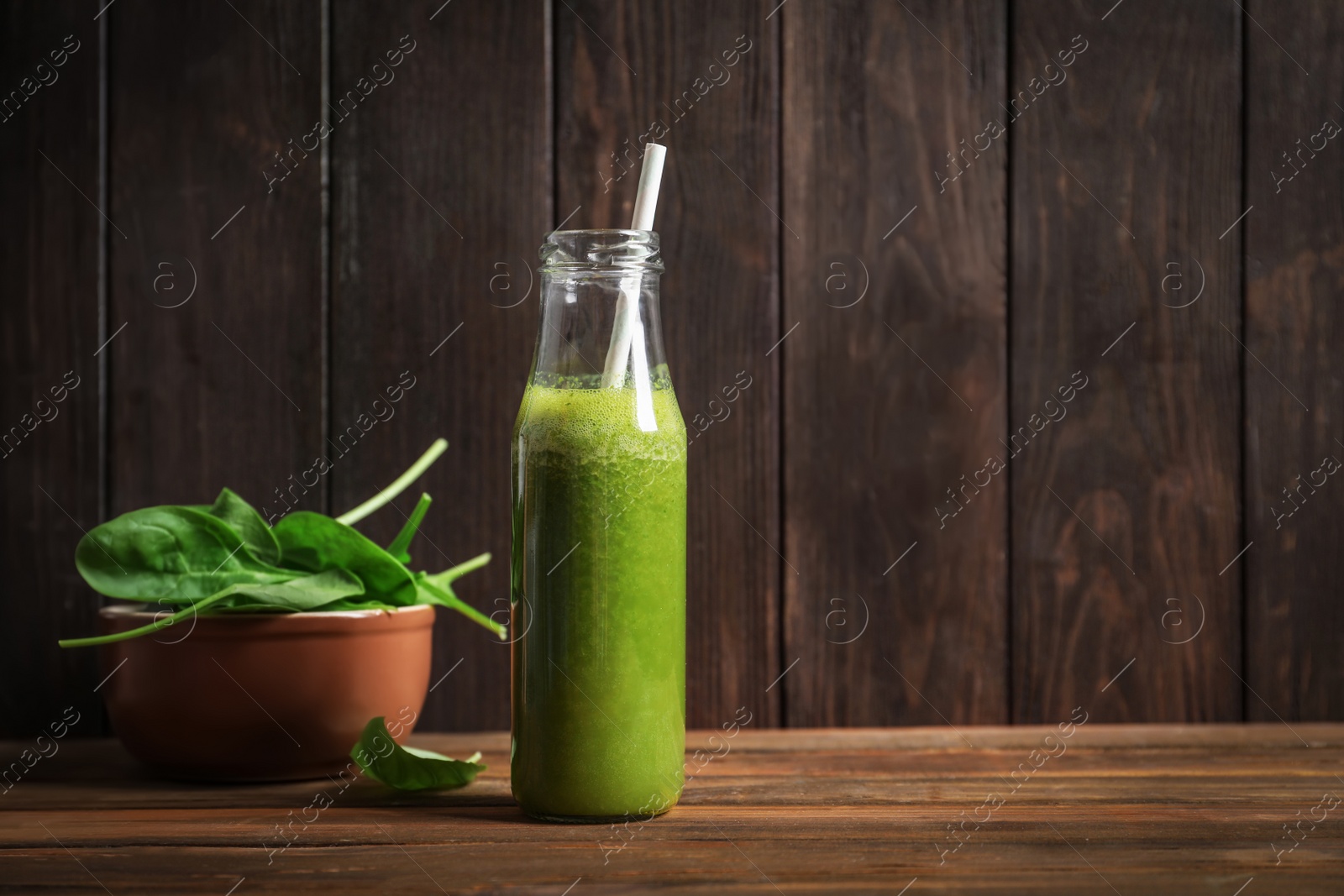 Photo of Bottle with delicious detox juice and spinach on table