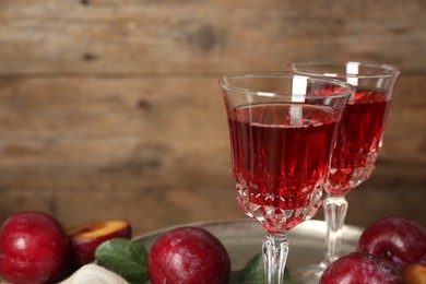 Delicious plum liquor and ripe fruits on wooden background. Homemade strong alcoholic beverage