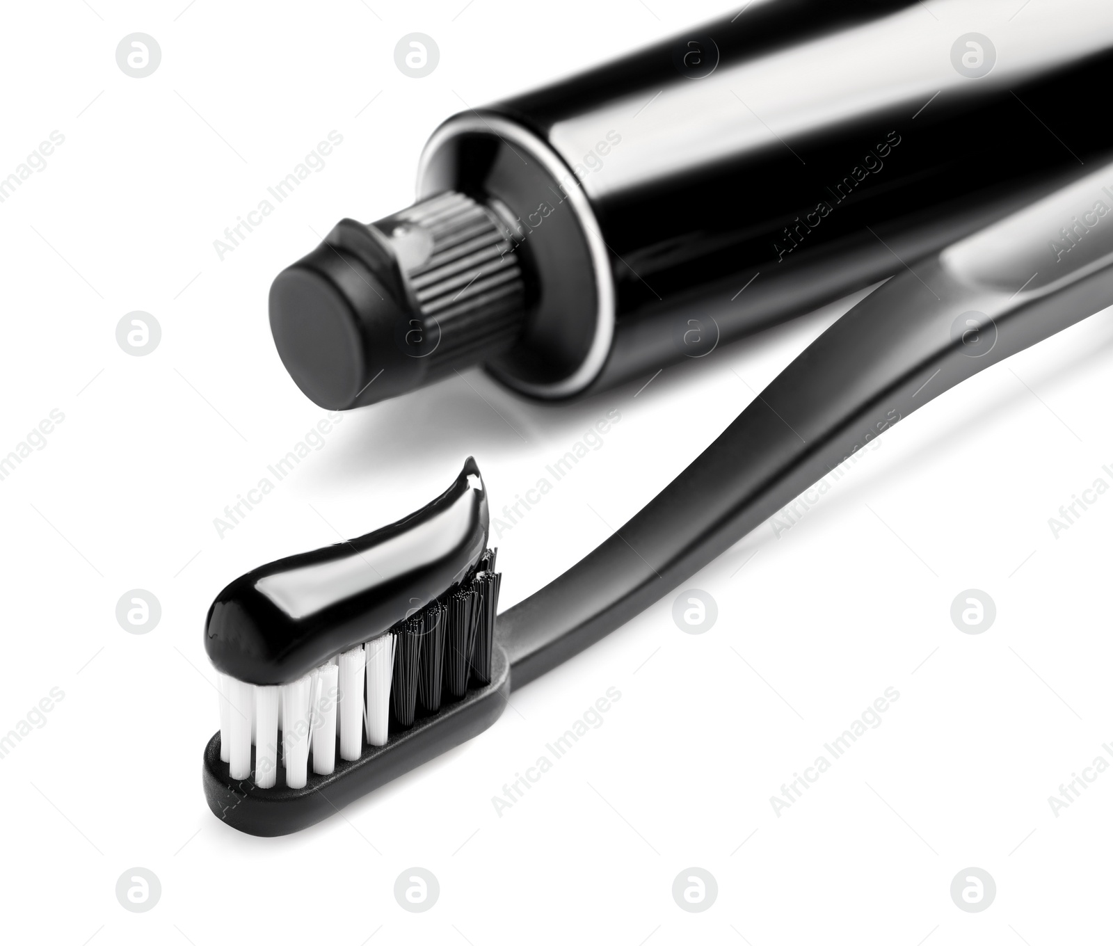 Photo of Tube of charcoal toothpaste and brush on white background