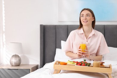 Photo of Smiling woman having breakfast in bed at home. Space for text